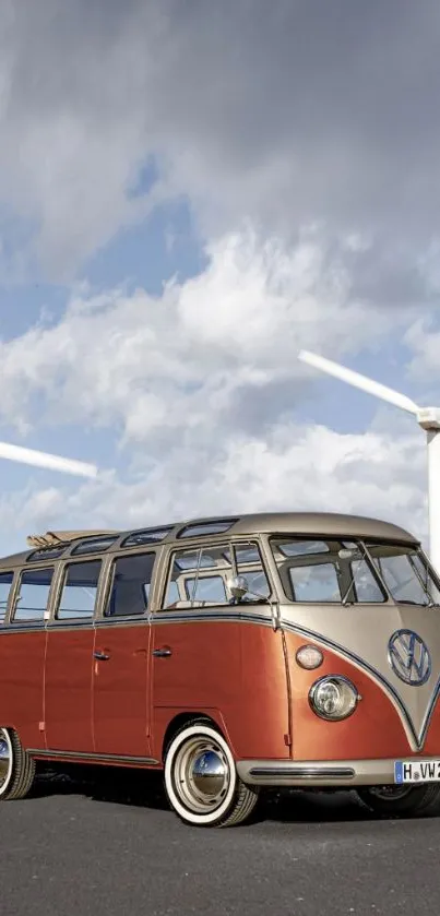 Vintage van under a cloudy sky with wind turbines in the background.