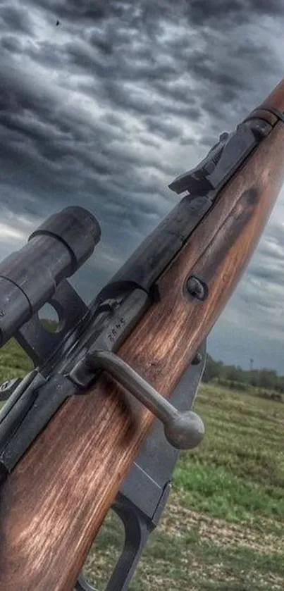 Vintage rifle against cloudy sky in field.