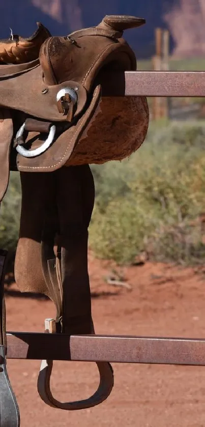 Old saddle hanging on a fence with desert background