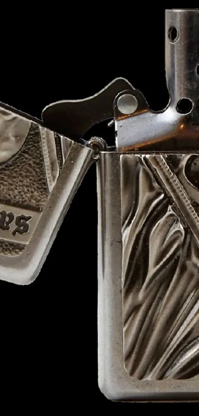 Open metallic lighter with skull and graphic engraving.