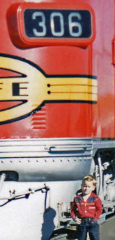 Vintage red train engine with child standing in front.