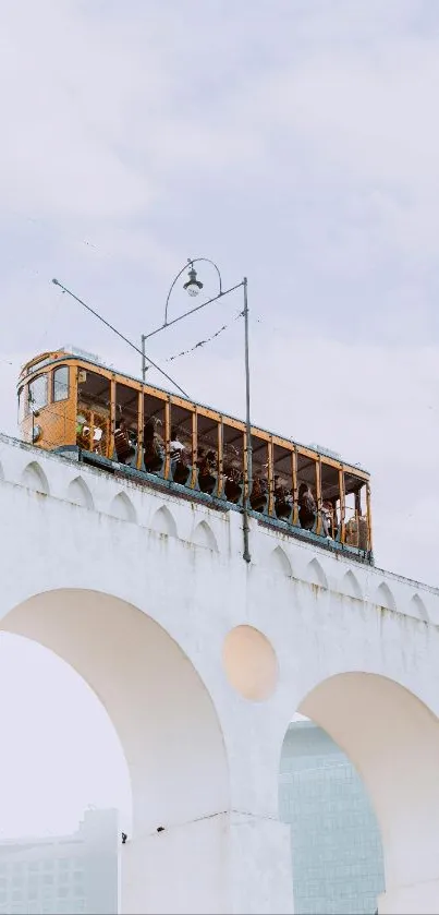 Vintage tram crossing the Lapa Aqueduct with clear sky backdrop.