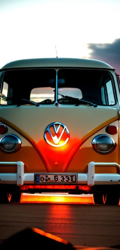 Vintage van on beach at sunset with orange and pink hues.