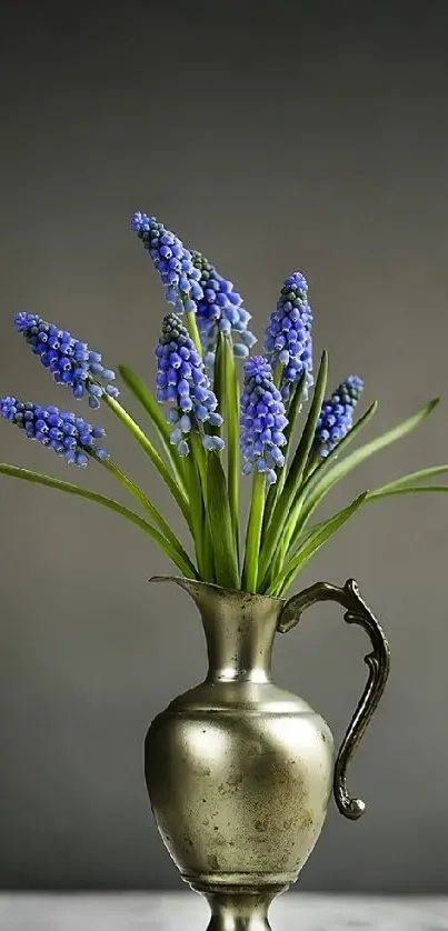 Vintage brass vase with blue flowers and green leaves.