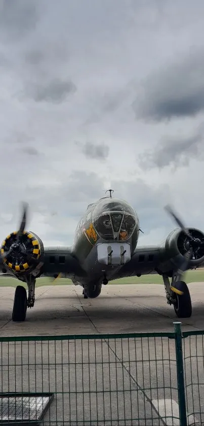 Vintage warplane parked on an airfield runway under cloudy skies.