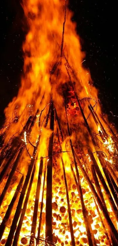 Blazing bonfire with vivid orange flames and burning sticks at night.