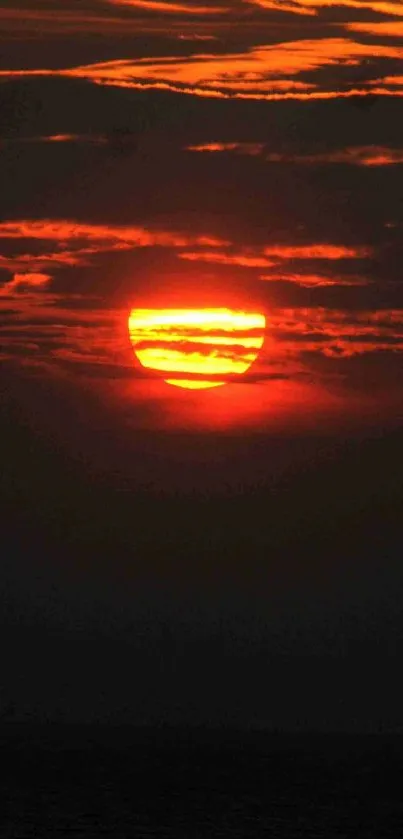 Vivid sunset over ocean with orange and red hues.