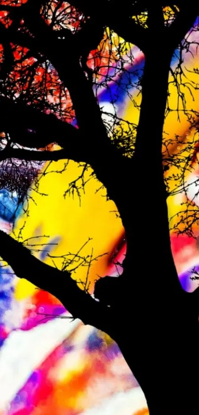 Silhouette of tree against vibrant, abstract colorful background.