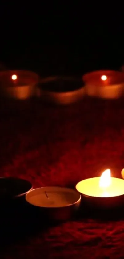 A row of flickering candles on a dark red background creates a warm ambiance.