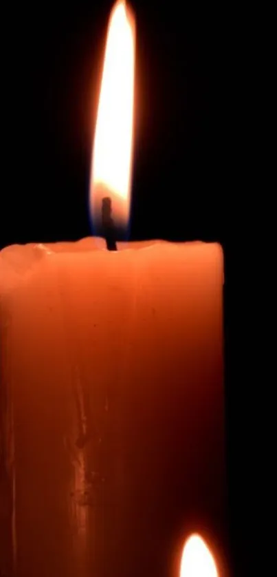 A candle with a warm, glowing flame against a dark background.