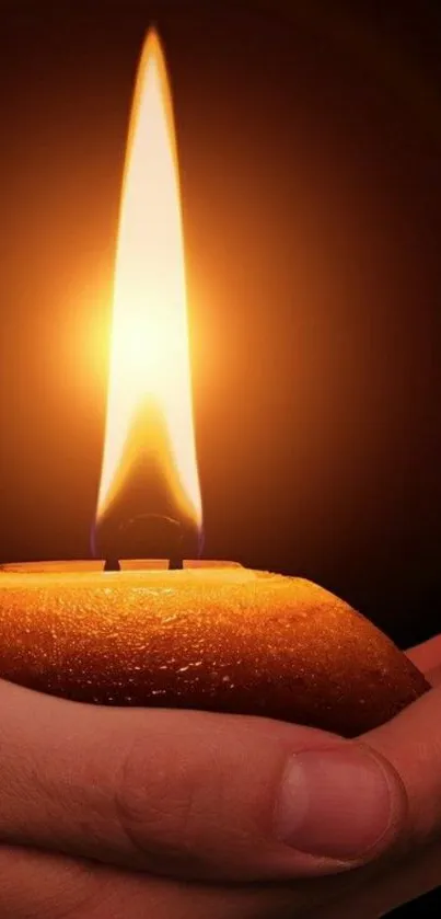 A glowing candle flame in a hand, emitting a warm orange glow.