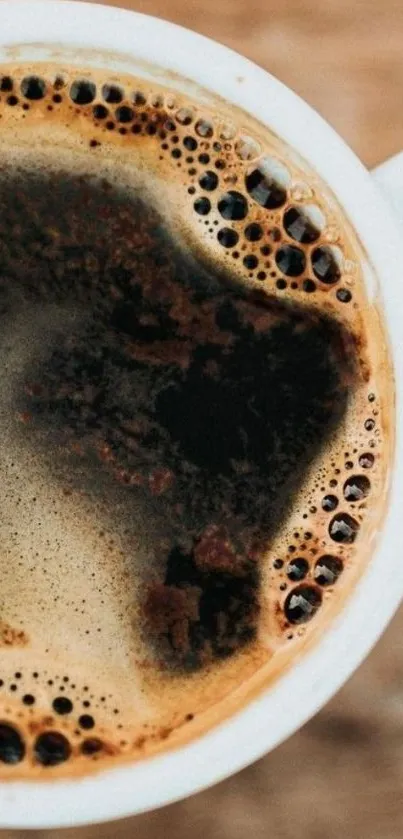 Close-up of coffee cup with dark brew and frothy bubbles.