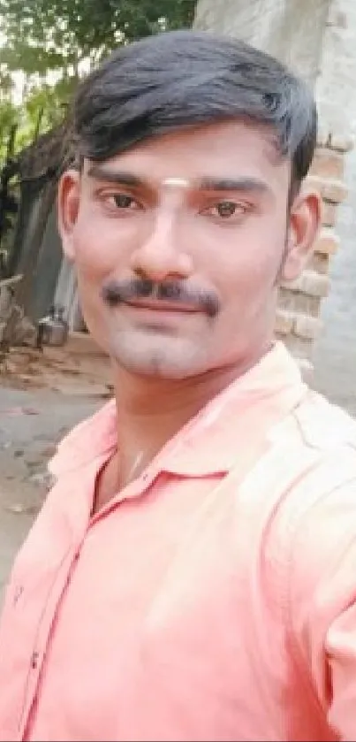 Portrait of a man in a coral shirt with a rustic urban background.