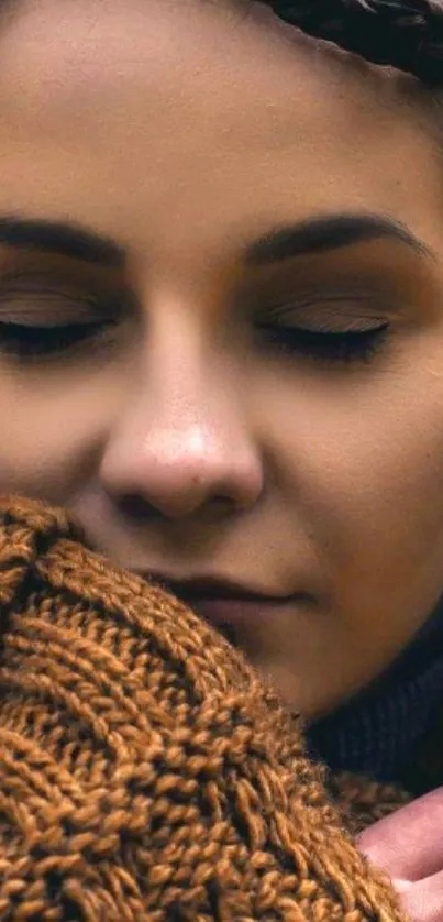 Close-up of a person embracing a textured brown sweater with a serene expression.