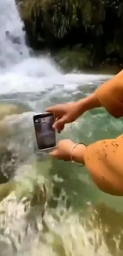 Holding smartphone near waterfall with lush greenery.