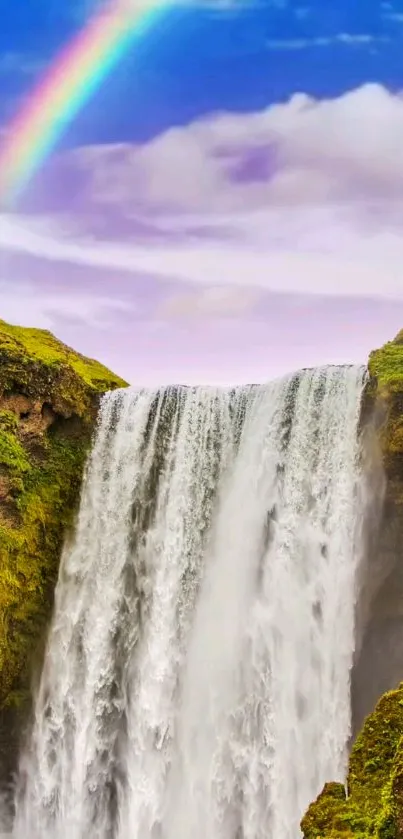 Waterfall with a rainbow over lush greenery and blue skies.