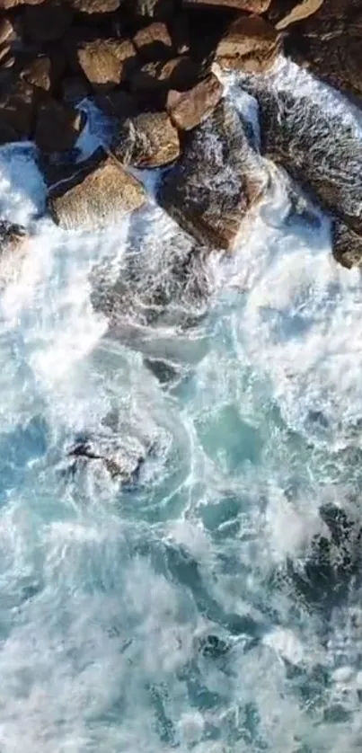 Aerial view of blue ocean waves crashing on rugged shoreline rocks.