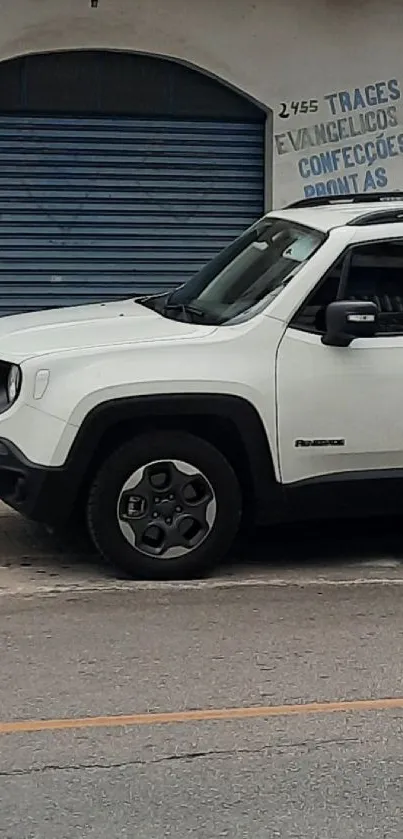 White SUV parked in front of a blue garage on a street.