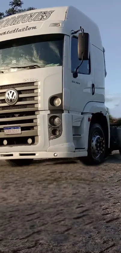 A white truck parked on a rural road under a clear sky in the background.