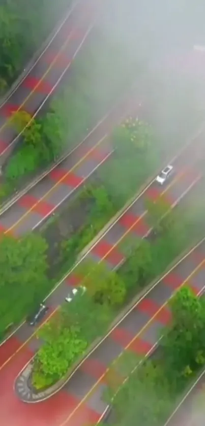 Aerial view of a winding road with mist and vibrant green landscape.