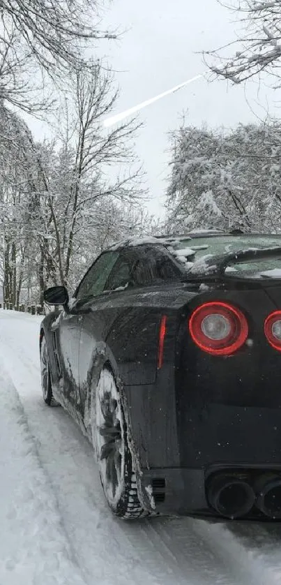 Black sports car driving on a snowy road through a winter landscape.