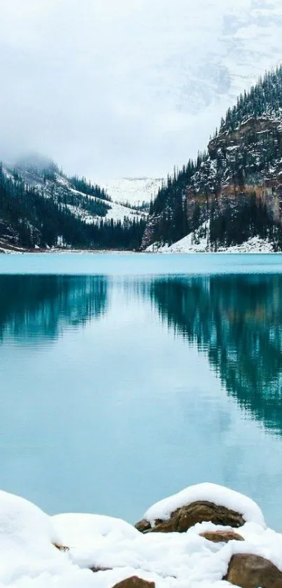 Serene winter lake with snowy mountains and turquoise waters.