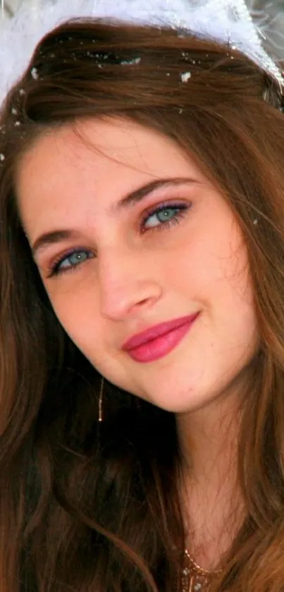 Portrait of a young woman with brown hair and blue eyes, surrounded by snow.