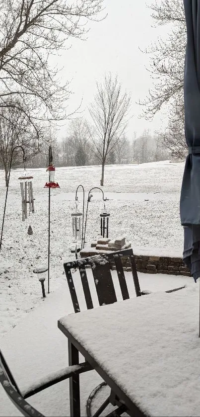 Serene garden with snow-covered tables and bare trees.