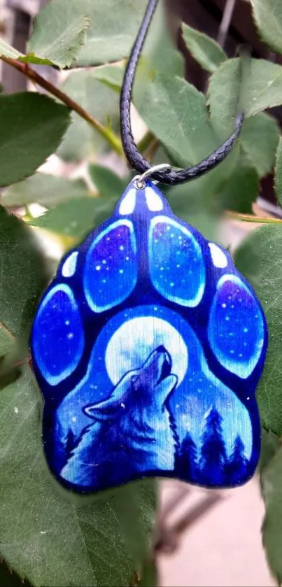 A wolf howling necklace with moon theme, set against green leaves.