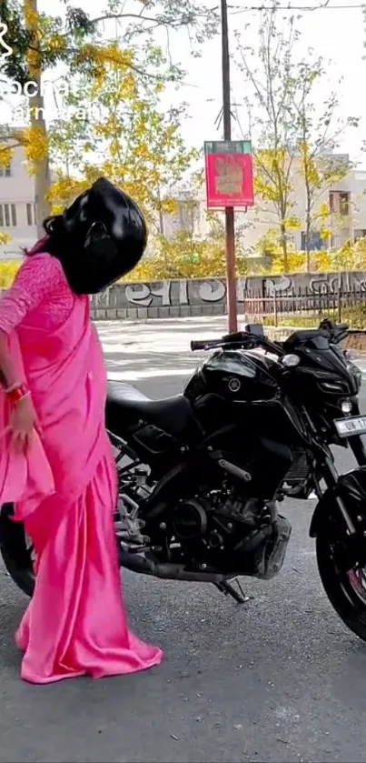 Woman wearing pink sari standing by motorcycle on the street.