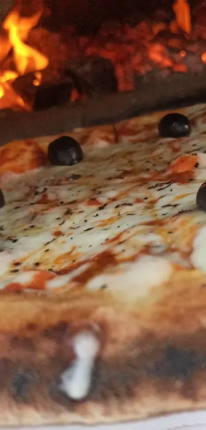 Wood-fired pizza with olives and a fiery background.