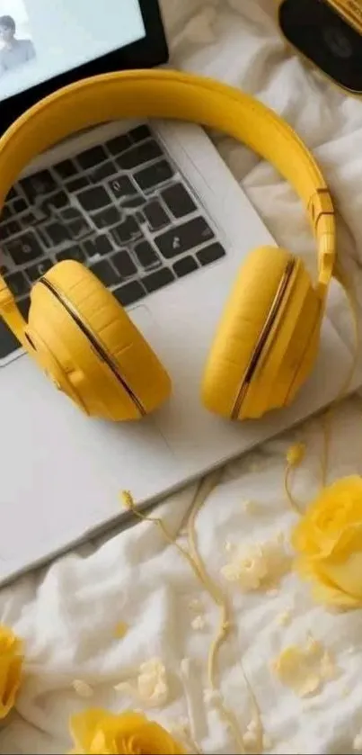 Yellow headphones on a laptop with roses on a bed, creating a cozy scene.