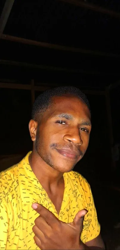 Man in yellow patterned shirt posing against dark background.