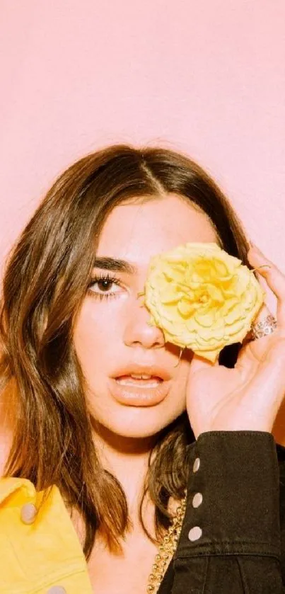 Woman with yellow rose against pastel pink background.