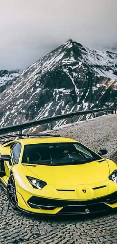 Yellow sports car driving on mountain road with snowy peaks.