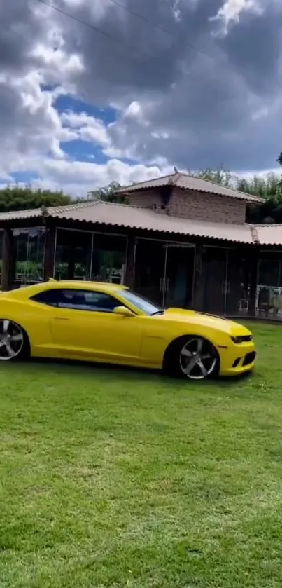 Yellow car on grass with house and cloudy sky background.