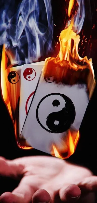 Burning Yin Yang cards floating above hand with vivid flames and contrast.