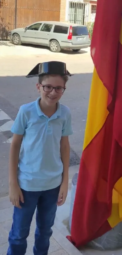 Young boy with hat, next to red and yellow flag.