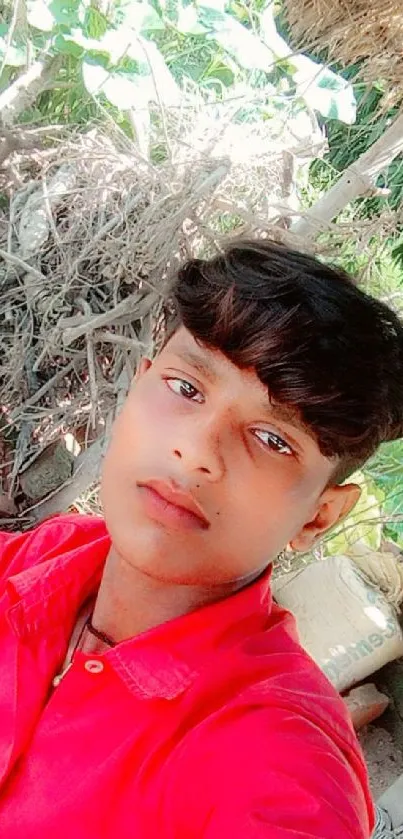 A young man in a bright red shirt outdoors.