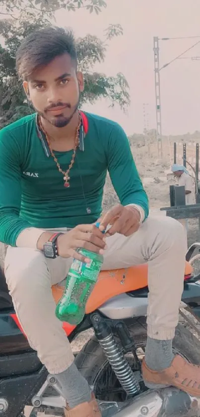 Young man sitting on motorcycle, wearing green shirt.