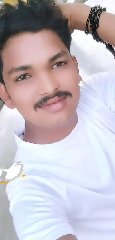 Young man in white shirt and bracelets outdoors.