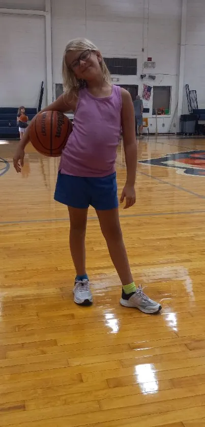 Young girl posing with basketball in a gym setting.