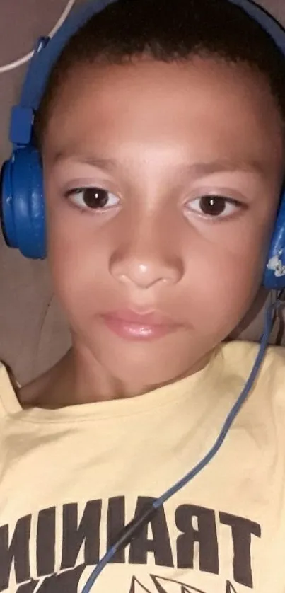 Young boy with blue headphones, relaxed pose.