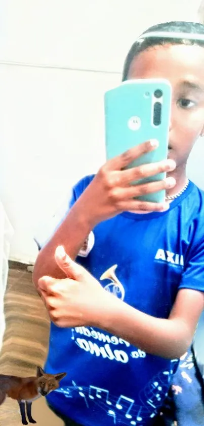 Young boy taking a selfie in a mirror, wearing a blue shirt.