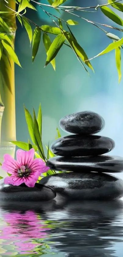 Stacked stones with bamboo and pink flower reflected in water.