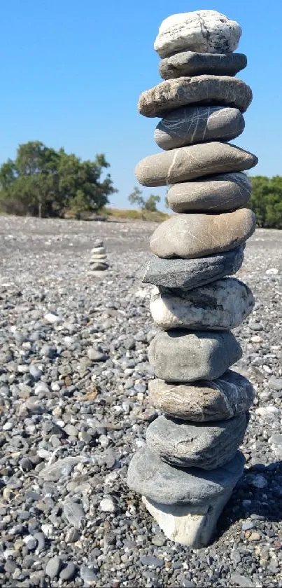 Stack of zen stones on a sunny beach with blue sky backdrop.