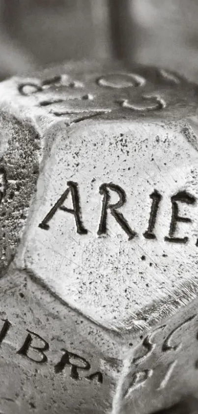 Close-up of a gray zodiac dice with Aries inscription.