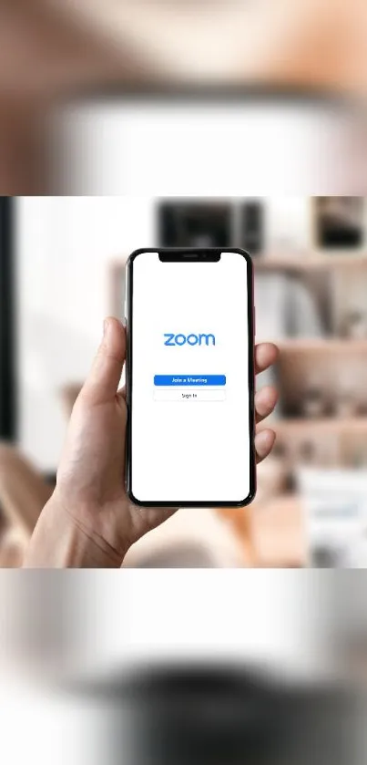 Hand holding smartphone displaying Zoom app in a modern room.