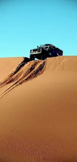 4x4 vehicle atop a sand dune under a clear blue sky in the desert landscape.