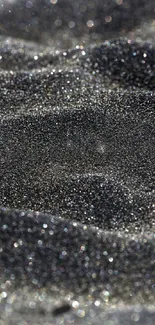 Close-up of glittering black sand texture in an abstract mobile wallpaper.